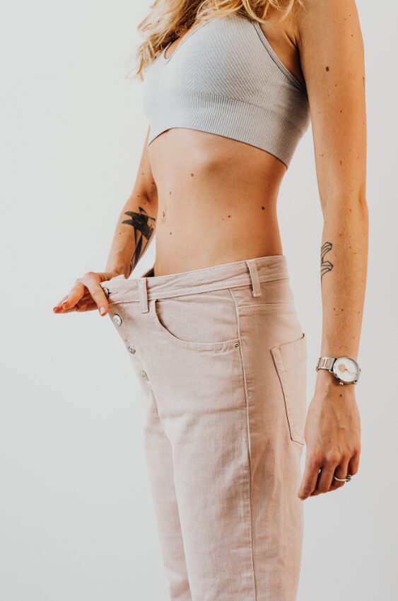 Woman holding out the waistband of loose jeans